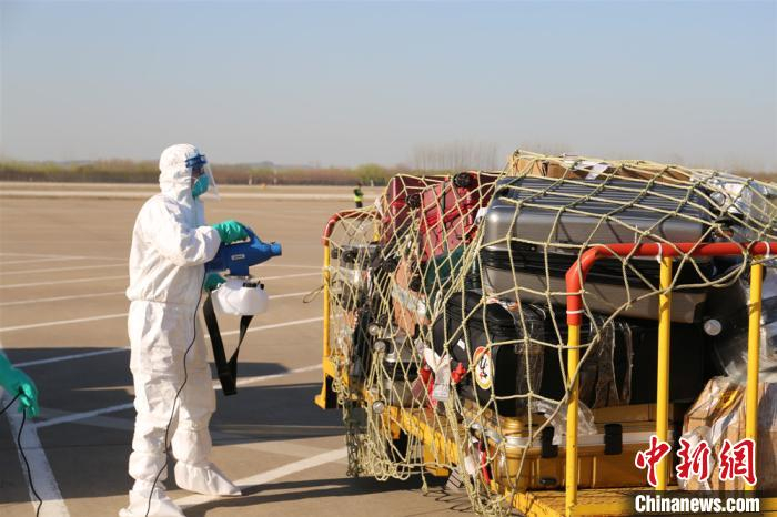 机场工作人员对运回的行李进行消毒。　姚焕鑫 摄