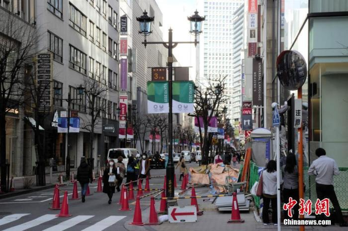 资料图：疫情下的日本东京街头，路面上挂着东京奥运的旗帜。中新社记者 吕少威 摄