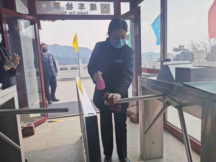 工作人员对缆车检票口基础设施进行消毒。新京报记者 王颖 摄