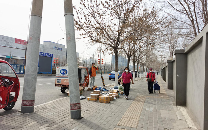允许快递员办出入证进小区后，京通苑小区南门外的快递“摆摊”量减少。摄影/新京报记者 陈琳