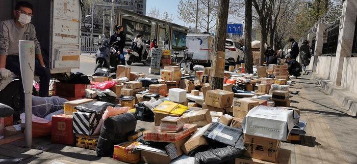 　　4月11日，朝阳区望京西园三区西门，各家快递公司的包裹摆满地，在人行道上延伸出去几十米。摄影/新京报记者 陈琳