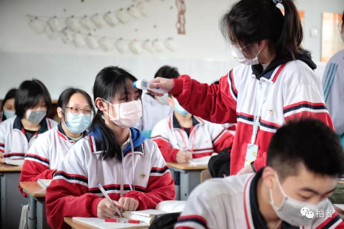 △ 班干部给同学测量体温。