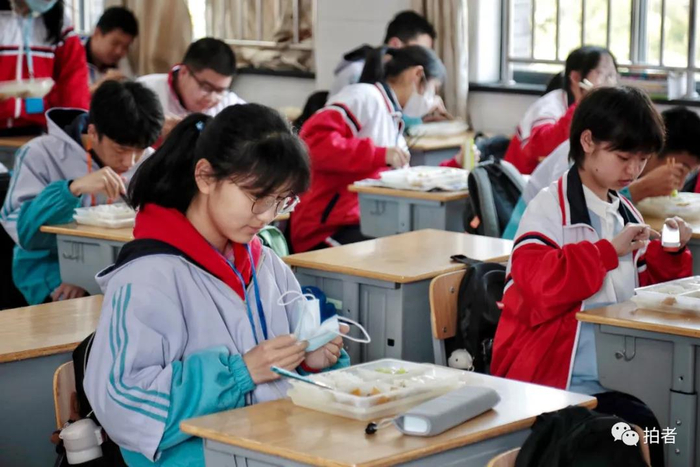 △ 午餐时间，学生摘下口罩，用自带的餐具吃饭。