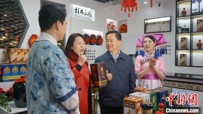 图为桂林市长秦春成(右二)向网友推荐“桂林三宝”之一的桂林三花酒。　欧惠兰 摄