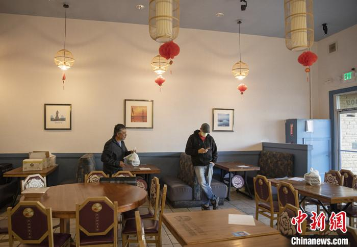 当地时间3月16日，一名戴口罩的顾客在美国旧金山湾区米尔布雷一家餐馆等餐。这家菜馆从当日开始实行“无接触取餐”，顾客网上下单，到店自取食物，饭店也可提供送餐服务。中新社记者 刘关关 摄