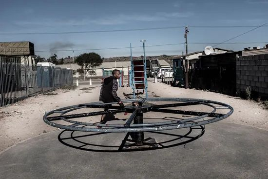  4月9日，南非德班维尔郊外一小镇，一名男子坐在儿童游乐设施上。新华社/法新