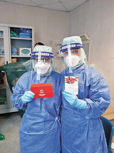 　　意大利医护人员身穿华人捐赠的防护装备，展示慰问信。