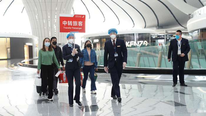 在北京大兴国际机场中转时，中联航地面服务人员引导旅客乘坐航班。中国联合航空供图