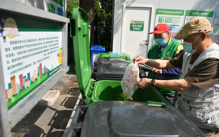 建钢南里社区垃圾分类指导员正在指导居民投放垃圾。摄影/新京报记者 吴江