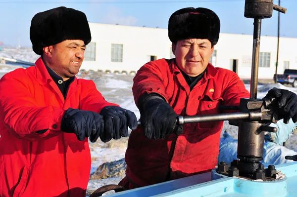 二名维族采油工人在检修井口设备（来源：中国日报）