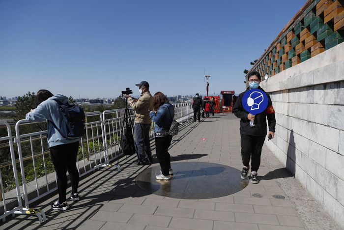 工作人员在万春亭景区提示游客戴口罩少聚集。新京报记者 侯少卿 摄