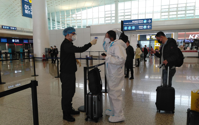 4月8日，武汉天河机场内，一位身穿防护服的乘客在安检口接受体温检查。新京报记者 海阳 摄