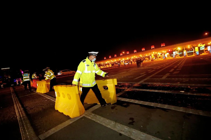 ▲4月8日零时许，汉蔡高速琴台收费站，交警搬开障碍物，准备指挥车辆离汉。摄影/无畏