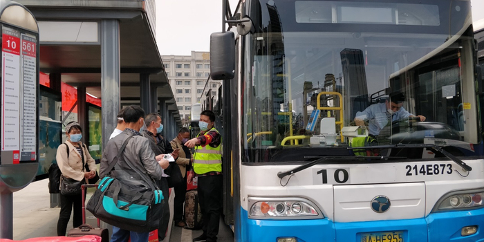  汉口火车站前的公交站停靠处，工作人员在指引乘客扫码乘车