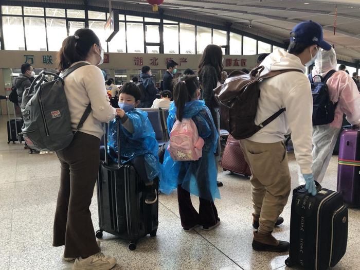  （穿着雨衣作为防护物的返京小旅客）