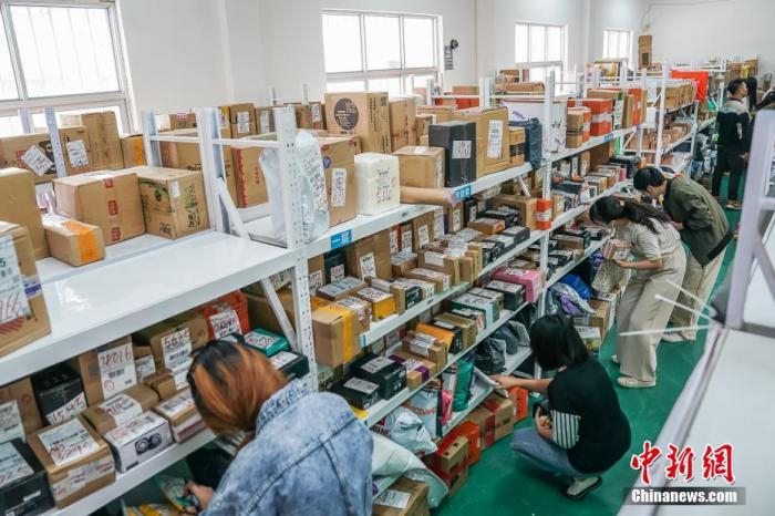 2019年11月15日，南宁，广西大学行健文理学院一个菜鸟驿站内，学生正按取件码寻找快递。中新社记者 陈冠言 摄