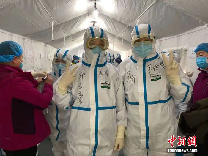 　　图为尹伶慧和队友穿好防护服，进方舱医院工作前，比出胜利的手势给自己加油。新疆巴州援助武汉医疗队供图
