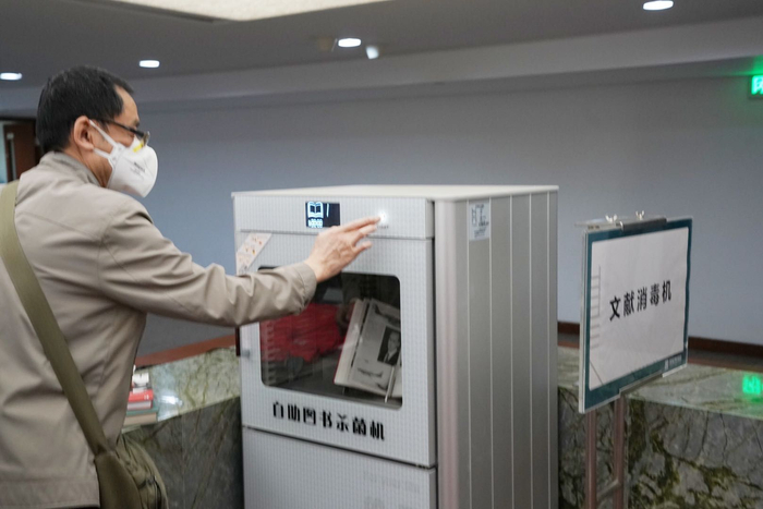 读者利用自助图书消毒设备为书籍消毒。新京报记者 浦峰 摄