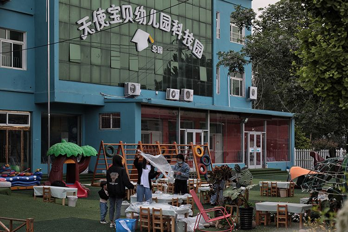 幼儿园老师们给大排档的小餐桌盖上一次餐布。