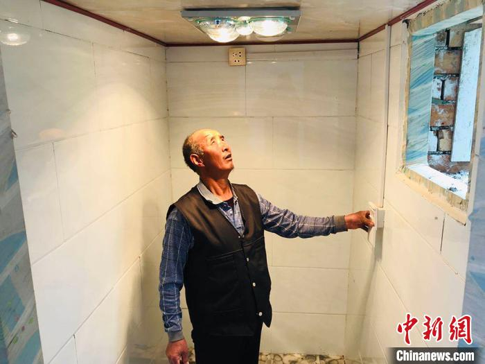     甘肃临夏州临夏县大沟村村民王西麦打开浴霸，眯着眼望着灯光。　艾庆龙　摄