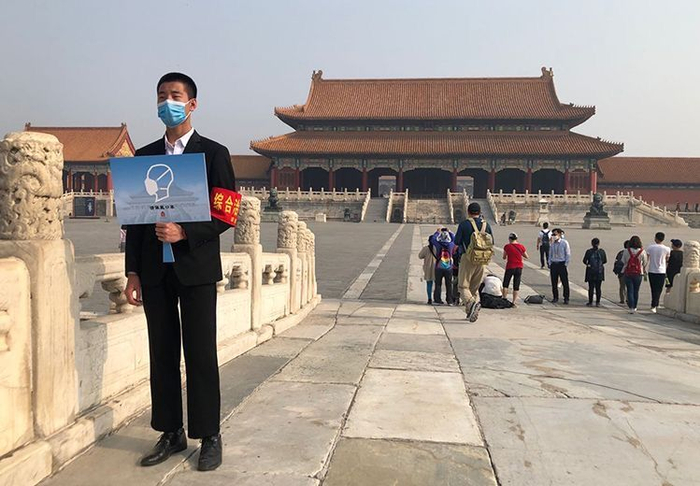  工作人员持牌提醒游客佩戴好口罩。摄/新京报记者 浦峰