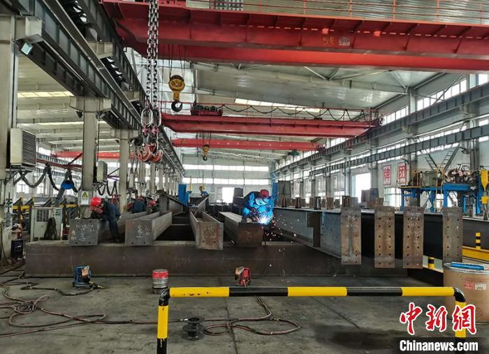 在新疆兵团乌鲁木齐工业园区内，工人们正在焊接钢材料。　戚亚平 摄