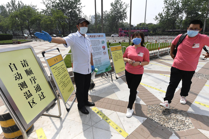 玉渊潭公园门口，马中原在引导游客入园。新京报记者 吴宁 摄