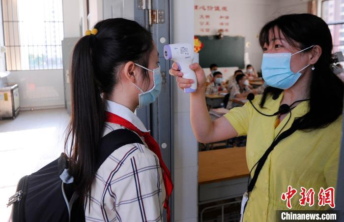 桂雅路小学桂花校区老师在校门给进入教室的学生测量体温。　蒋雪林 摄