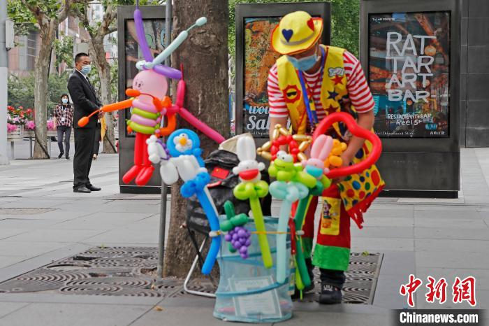 街头艺人戴着口罩正在静安寺商圈表演。　殷立勤 摄