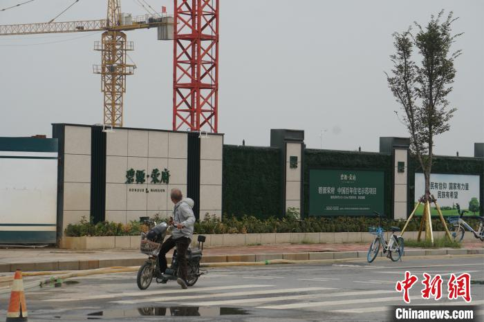 资料图，郑州北龙湖一市民路过在建楼盘。　董飞 摄