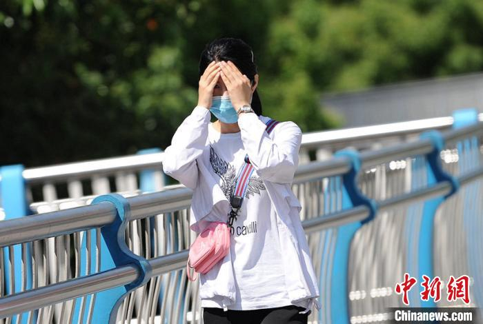 图为贵阳市民穿戴防晒服饰出门。 石奎 摄