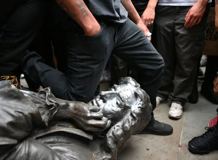 英国抗议者用膝盖跪在雕像脖子上。/《卫报》视频截图