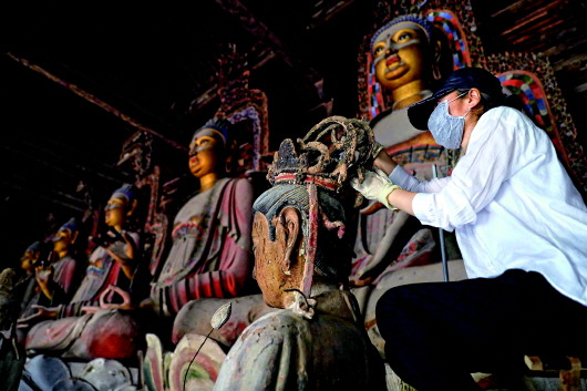 　　▲6月8日，工作人员对奉国寺的彩绘泥塑进行保护修复。记者姚剑锋摄