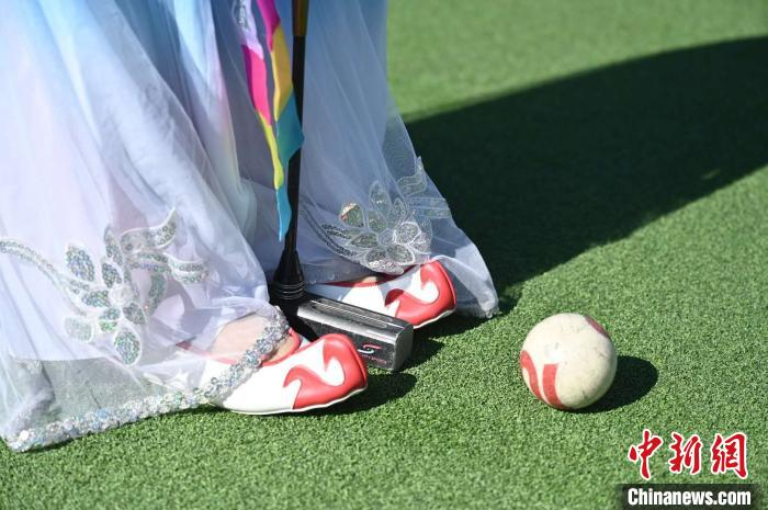 身穿民族传统服饰的星火村村民在挥杆击球。　张兴龙 摄