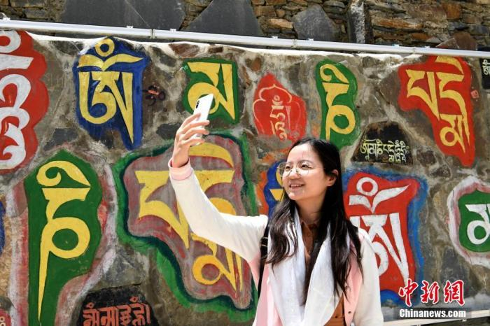 图为6月13日，游客在石刻碑文墙前自拍留念。 中新社记者 安源 摄