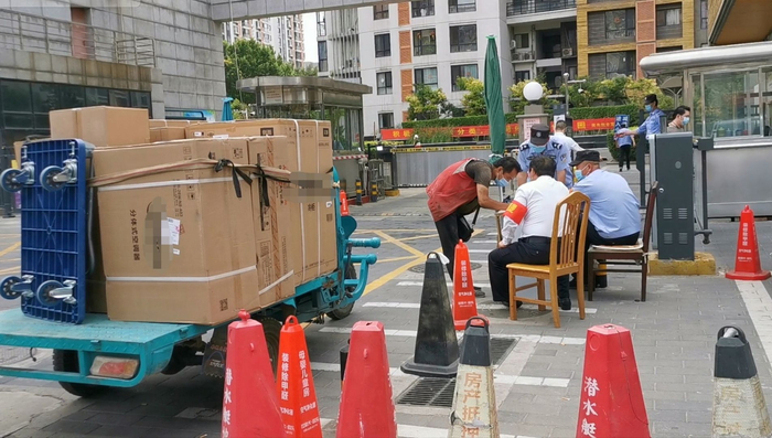 朝阳区风度柏林小区门口，一家电配送人员正进行信息登记并等待住户前来签字带人进门。新京报记者 马瑾倩 摄