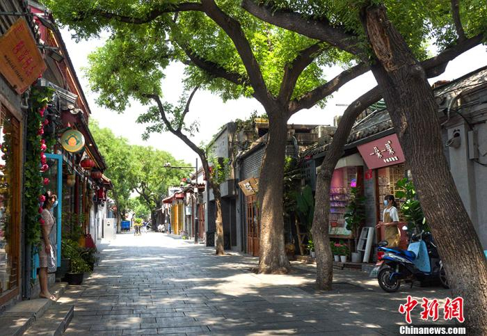  6月18日，南锣鼓巷两家商铺的店员在各自门口隔路聊天。中新网记者 李霈韵 摄