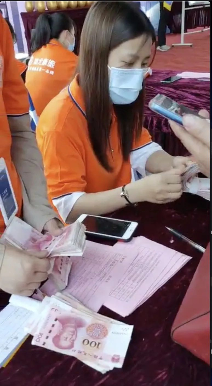 ▲现场工作人员收取学员现金。蚩尤康旅微信群