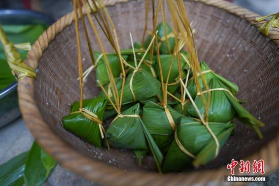 资料图：2019年6月6日，贵州黎平县三龙侗寨侗族妇女包的棕子。在当地，端午时节，侗族妇女采摘竹叶包粽子迎端午节，庆祝“关秧门”。中新社记者 贺俊怡 摄