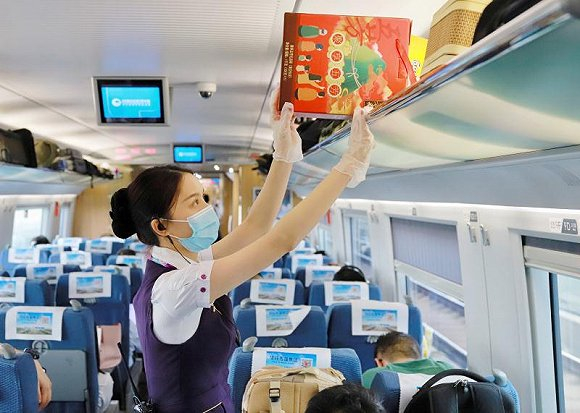 一名杭州客运段乘务人员在高铁列车上整理行李架物品。  摄影：周围  