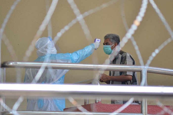 　　当地时间4月14日，在马来西亚吉隆坡一处因新冠确诊病例被封锁的住宅楼，一名医务人员为住户测量体温。 新华社 资料图