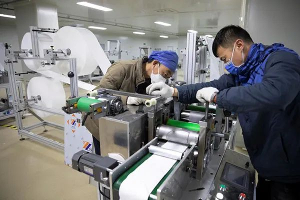 疫情期间，亿信医疗器械公司技术人员正在安装口罩机。资料图