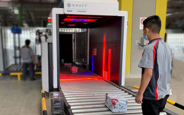 货物代理人员将已申报货物放入扫码机进行货物信息采集，随后货物进入安检机。首都机场集团公司供图