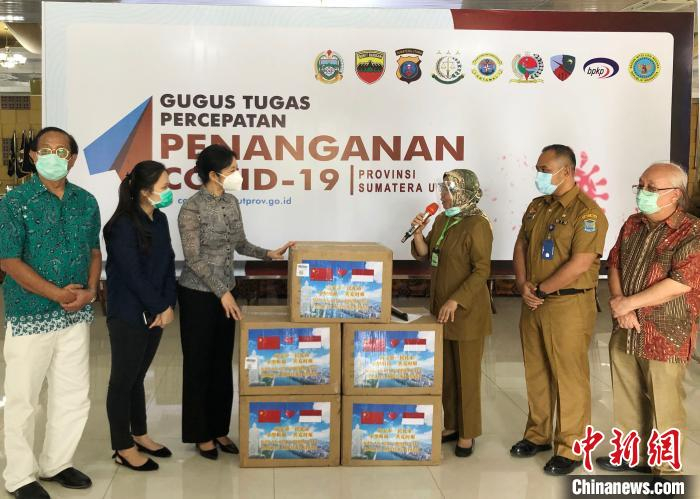 图为邱薇薇将中国福建省南安市政府通过苏北省政府对外友好协会捐赠的3万个医用口罩移交莎白莉娜后转交给达务来。印尼苏北省政府对外友好协会 供图