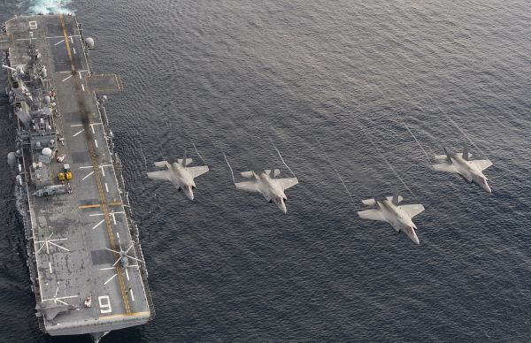 资料图片：美海军陆战队F-35B编队飞越“美利坚”号两栖攻击舰。（美海军官网）