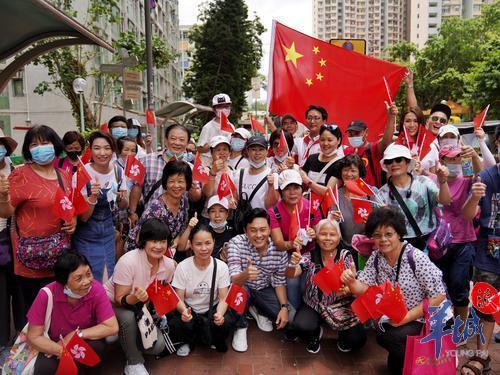 香港九龙黄大仙下邨，众多居民手拿国旗欢迎巡游花车