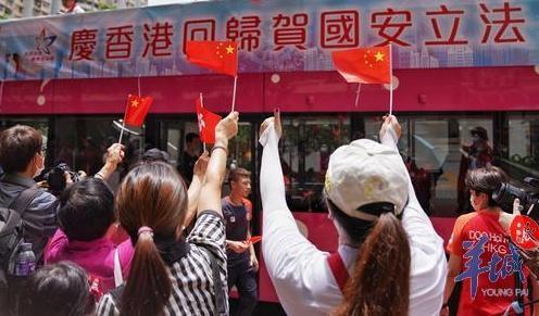 香港九龙黄大仙下邨，众多居民手拿国旗欢迎巡游花车