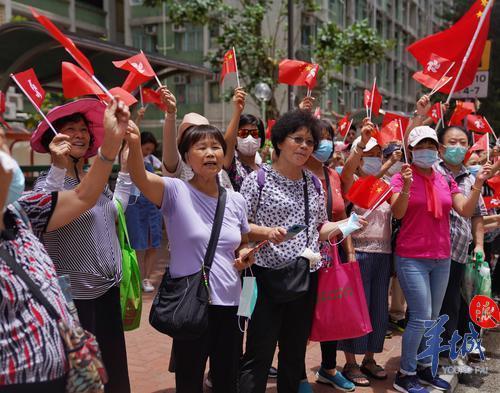 香港九龙黄大仙下邨，众多居民手拿国旗欢迎巡游花车