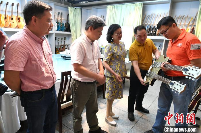 吕孟哲(右)向客人介绍他的乐器产业。　王东明 摄