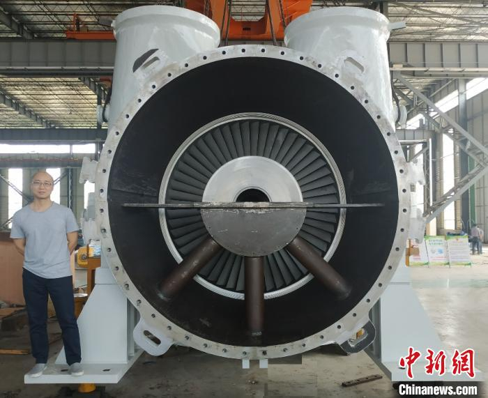 国际首台100MW先进压缩空气储能系统膨胀机正面，科研人员留影。(中科院工程热物理所 供图) 